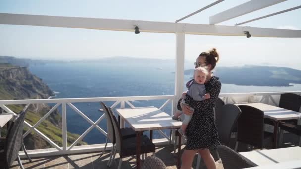 Mamma cammina con il bambino tra le braccia in un posto bellissimo, una bella terrazza con vista sul mare — Video Stock