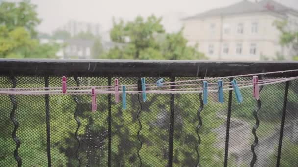 Certaines pinces à linge colorées pendent sur la ligne de lavage sous la pluie battante. Mouvement lent — Video