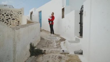 Santoron adasının merdivenleri üzerinde bir Sling ayakta bir bebek ile kız