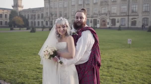 Una joven pareja sueca casada original de pie frente al castillo y girando la cabeza en una dirección — Vídeos de Stock