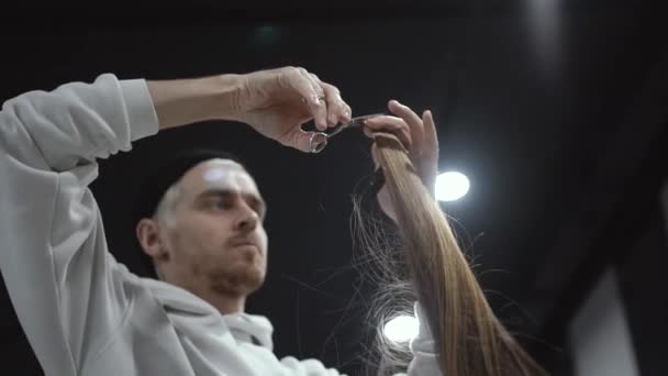 A middle plan of a male hairdresser cutting a lock of blonde hair — Stock Video