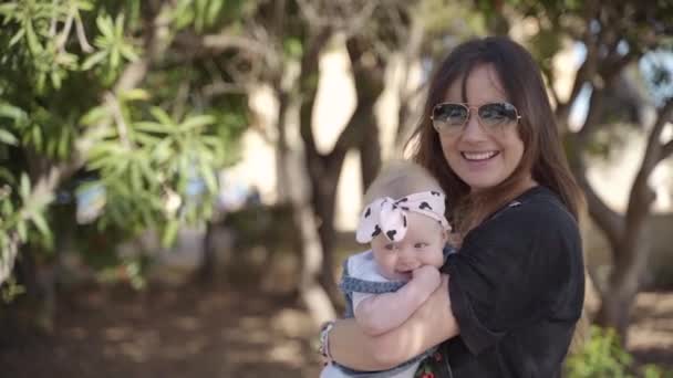 Une jeune famille comprenant une mère et sa fille tourbillonnant et sautant entourée d'arbres sur Malte — Video