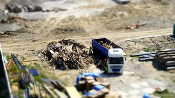 Uitzicht op de bouwplaats waar werknemers zijn lading lamber in dump truck — Stockvideo