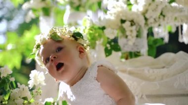 Bir kız bebek yakın çekim portresi. Çiçeklerle çiçekli dekorasyon oturan güzel küçük kız. C