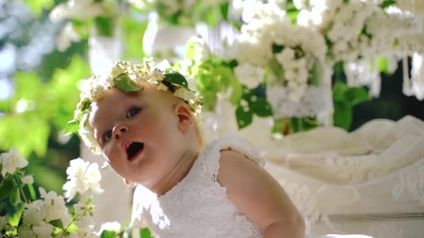 Un retrato de cerca de una niña. Hermosa niña sentada en la decoración florida en flores. c) — Vídeo de stock