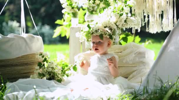 4k portret van kleine schattige baby. Mooie decoratie met witte bloemen, Wigwam en vliegende ballonnen — Stockvideo