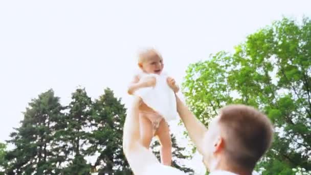 Lassított, Bezárás fel. A fiatal apa feldobás fel és le az édeskés kislány a helyi parkban. Lassított mozgás — Stock videók