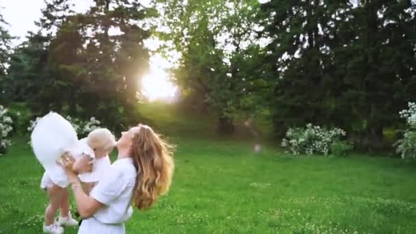 Junge Mutter und ihr Baby genießen den Sonnenuntergang in der Natur an einem Sommertag. glückliche Familie, die draußen spazieren geht. die Mutter, die Spaß daran hat, das Baby in die Luft zu werfen. Zeitlupe 120 fps, — Stockvideo