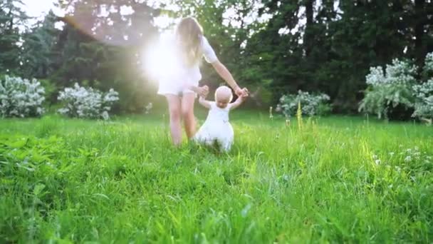 Молода мама вчить дитину ходити по зеленій траві в повільному русі . — стокове відео