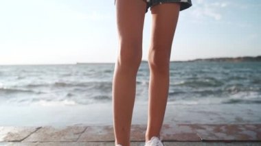 Deniz kenarında duran göğsünde çapraz elleri ile genç kız