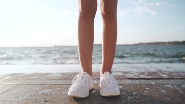 Ragazza in scarpe da ginnastica bianche contro il mare — Video Stock