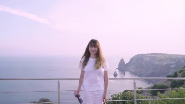 Junge erwachsene Frau mit Sonnenbrille, die am Meer steht — Stockvideo
