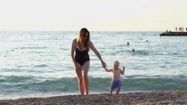 Deniz kenarında kızıyla el ele tutuşan anne