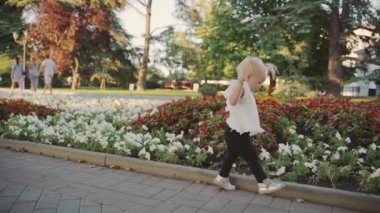 Çiçekli çiçek tarhına yakın açık havada yürüyen küçük kız bebek