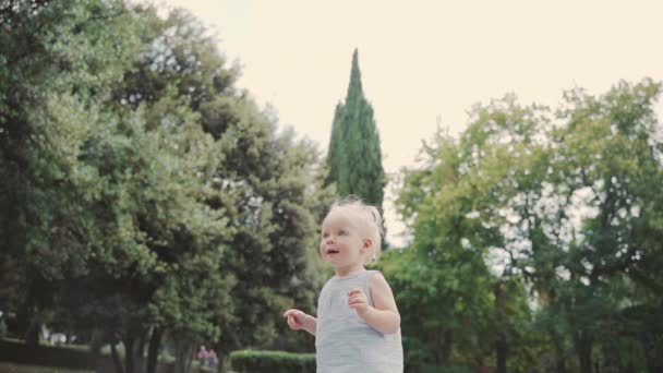 Маленький малюк гуляє по міському парку — стокове відео