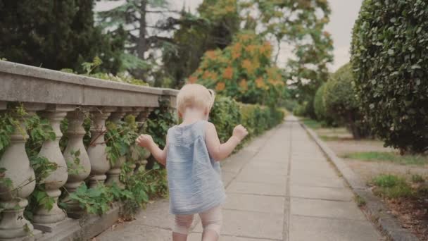 Маленькая девочка выходит на улицу в летний солнечный день — стоковое видео