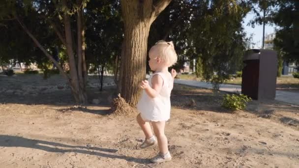 Niña pequeña caminando en el parque de la ciudad cerca del árbol — Vídeos de Stock