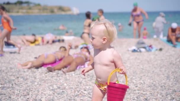 Kleine baby meisje spelen met emmer op strand — Stockvideo