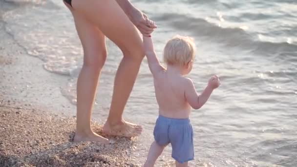 Small child girl and young adult mother standing near sea
