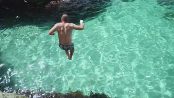 Hombre joven adulto saltando en agua cristalina del océano — Vídeos de Stock