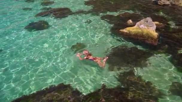 Mujer joven adulta en traje de baño nadando en el mar con agua clara — Vídeos de Stock