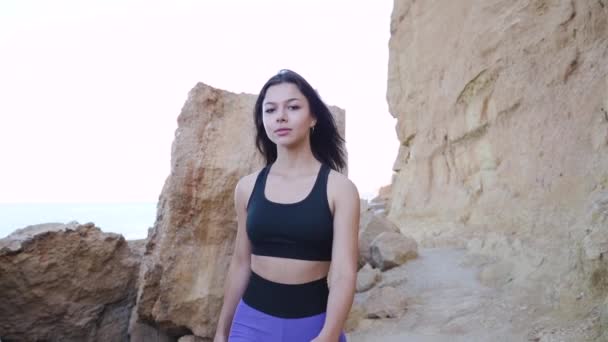 Jong volwassen atletisch meisje wandelen in de buurt van rotsachtige bergen — Stockvideo