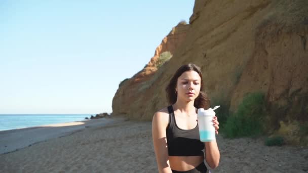 Mladý dospělý atletický žena pití vody po tréninku — Stock video