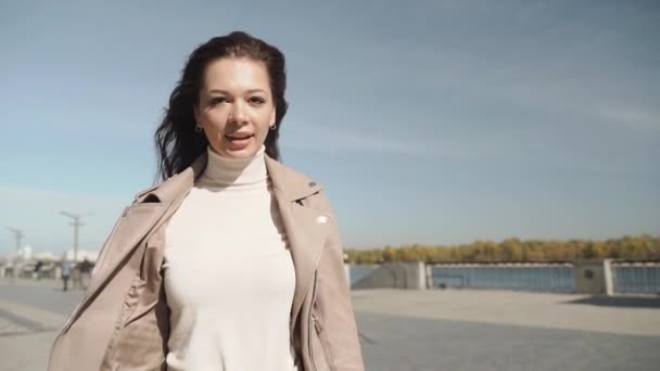 Junge erwachsene Frau blickt in die Kamera und läuft in der Stadt — Stockvideo