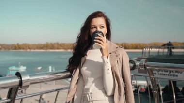 Genç bayan kağıt bardaktan içecek içiyor.