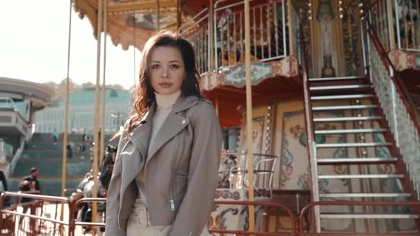 Jong volwassen vrouw kijken naar camera, staan in de buurt van carrousel — Stockvideo