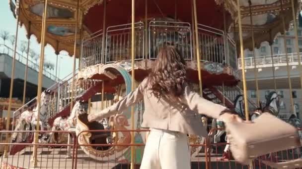Jonge volwassen dame draait rond, staan in de buurt van carrousel — Stockvideo