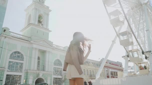 Young adult girl walking near ferris wheel in city — Stock Video