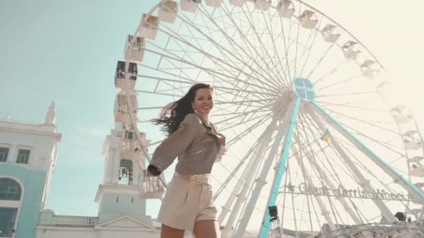 Menina adulta jovem sorrindo largo e andando perto da roda gigante — Vídeo de Stock