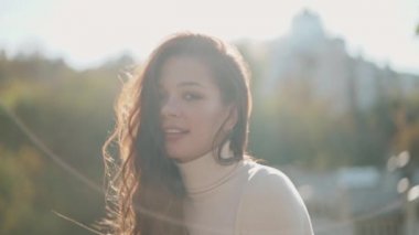 Genç bir kadın kameraya bakıyor ve gülümsüyor.