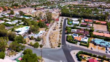 Hava aracı görüntüleri Palm Springs, Kaliforniya 'da bir yerleşim bölgesinde ilerliyor. Beyaz çatılı evler, palmiyeler ve çöl bitkileri gün ışığında görülebilir. San!