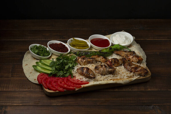 lamb tikka kebab on rice servid with fresh vegetables and sauces