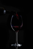 červené víno se nalévá na sklo s dlouhým stonkem v tmavé
