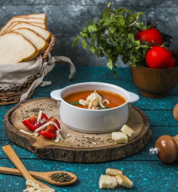 Rendelenmiş peynir ve ekmek ile süslenmiş domates çorbası.