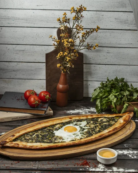 Pide d'épinards avec oeuf sur plateau de service en bois — Photo gratuite