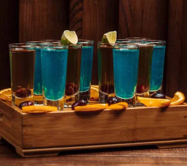 Shots of blue lagoon and grape drink garnished with lime — ストック写真