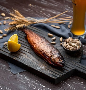 Limonla servis edilen kuru balık, şam fıstıklı tahtanın üstünde, bira.