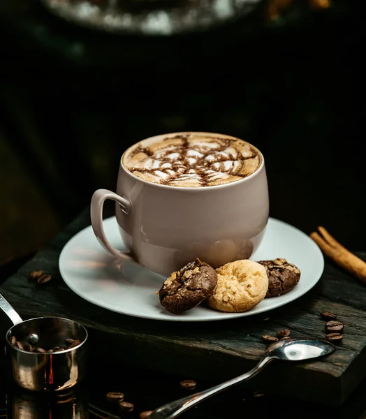 Стакан маккиато с шоколадным и молочным печеньем, на темном фоне — стоковое фото