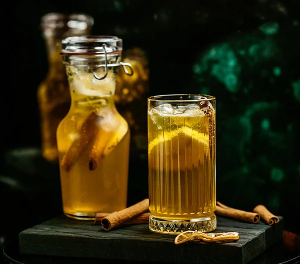 Honey cinnamon lemon drink in glass and hermetic glass jar in dark background — Stock Photo, Image