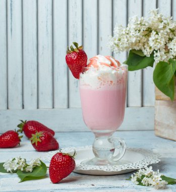 Çilekli milkshake, çırpılmış krema, çilek şurubu, açık arkaplanda çilek.