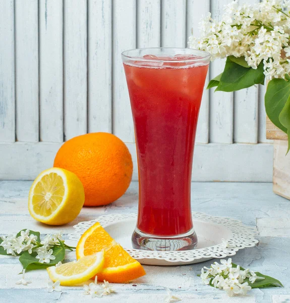 Orange and lemon juice in tall glass with ice cubes in light background — Stock Photo, Image