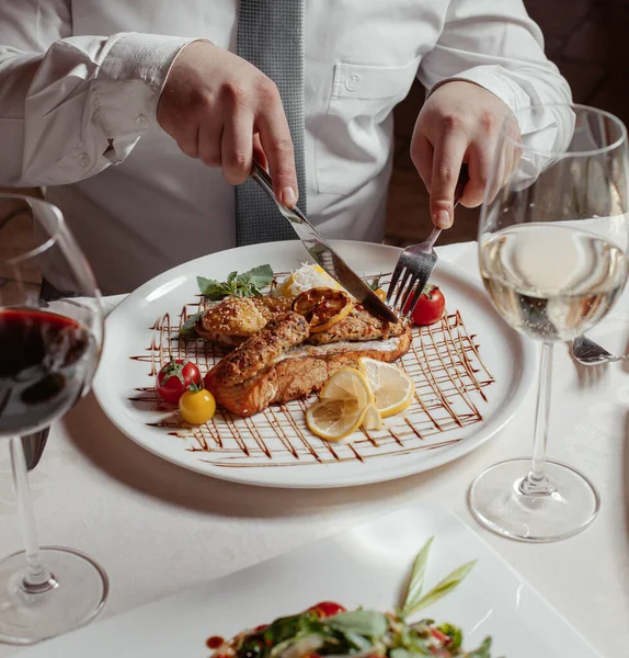 Mann schneidet gegrillten Lachs mit Reis, Lula Kebab, Läusen, Tomaten, Wein serviert — Stockfoto