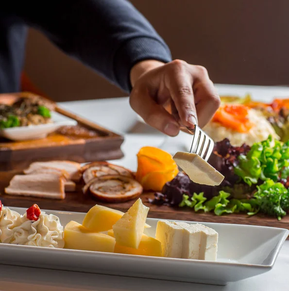 Mann nimmt Käse von Käseteller mit weißem Käse, Cheddar, Frischkäse — Stockfoto