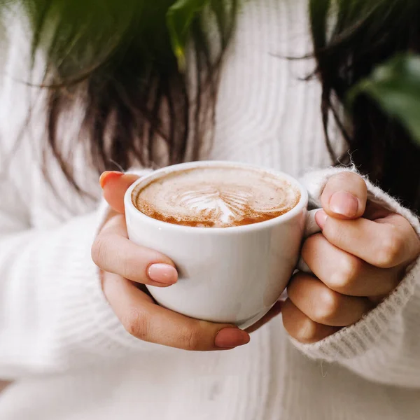 Mulher segurando xícara de café quente em jaqueta de malha branca — Fotografia de Stock