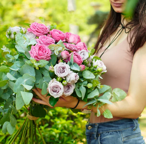 woman holding pink roses bouquet with eucalypt leaves in the garden