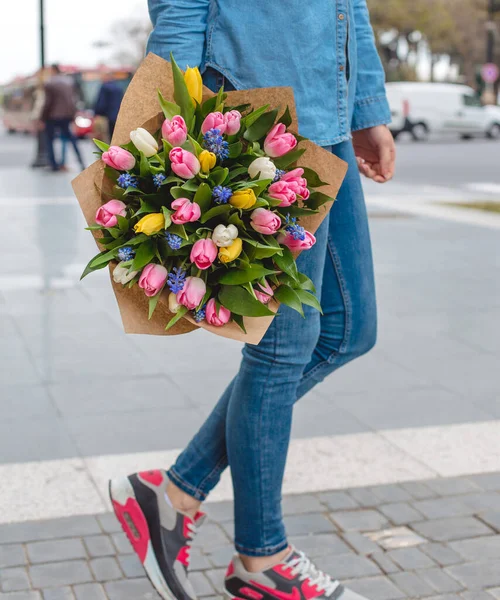 Женщина держит букет тюльпанов с розовыми, белыми, желтыми тюльпанами на улице — стоковое фото